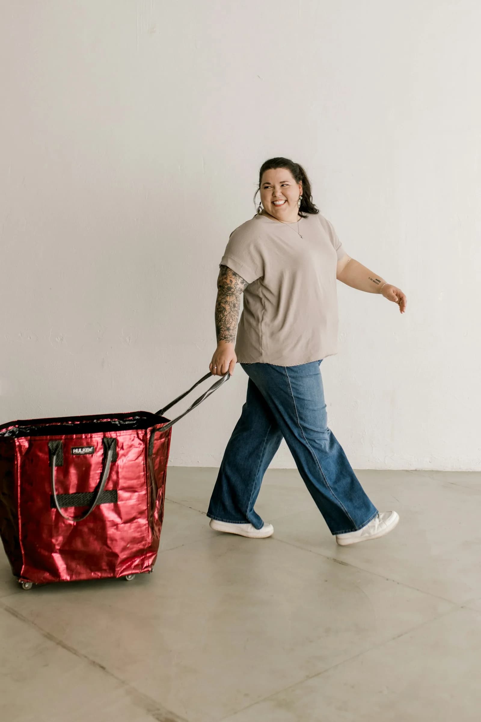 Mulher sorridente a puxar um saco de rodas vermelho